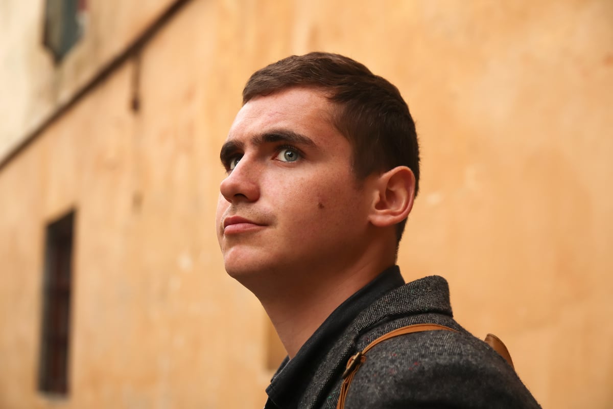 Portrait young man on aged yellow background. Serious young man. 20s years. Handsome man outdoors portrait. Walking lifestyle. Student. Out of focus